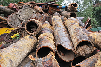 Pile of rusty industrial pipes and scrap metal in junkyard