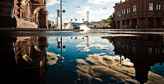 Urban street reflection with car splashing through puddle