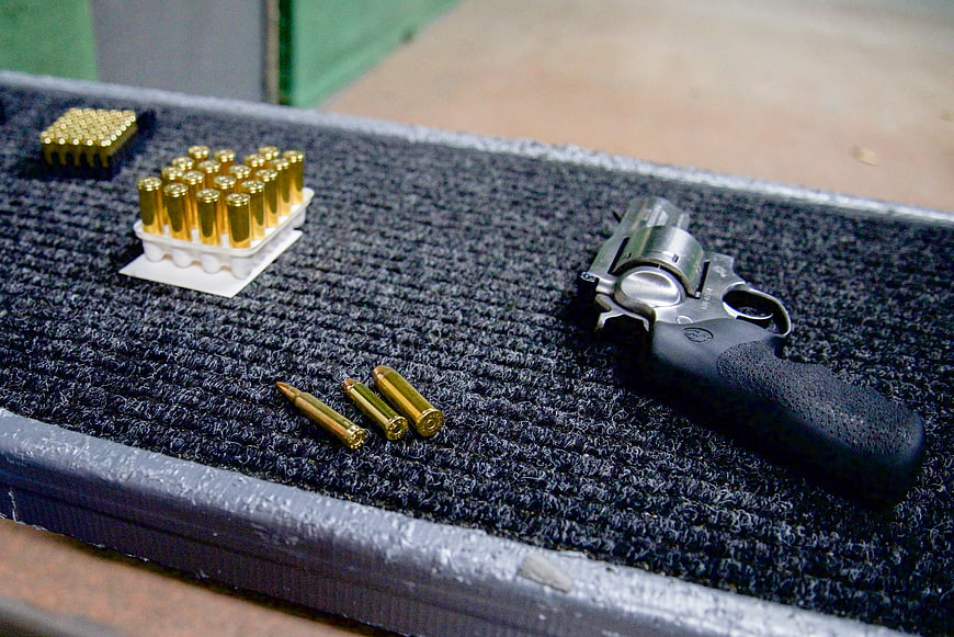 Silver revolver and ammunition on shooting range mat