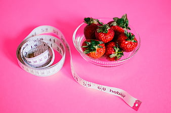 Strawberries and measuring tape on pink background