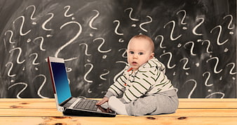 Baby using laptop with question marks on chalkboard background