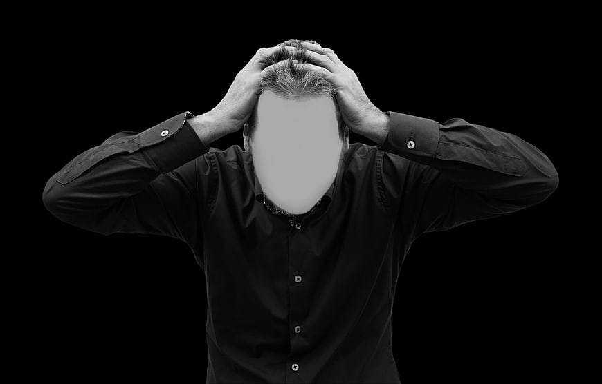 Stressed man holding head in black and white studio portrait