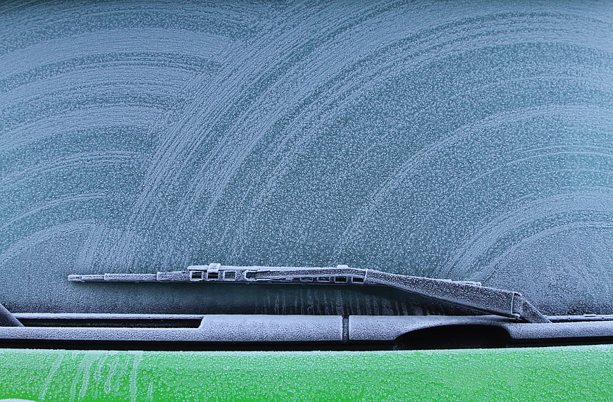 Frosty Car Windshield with Wiper Blades in Winter