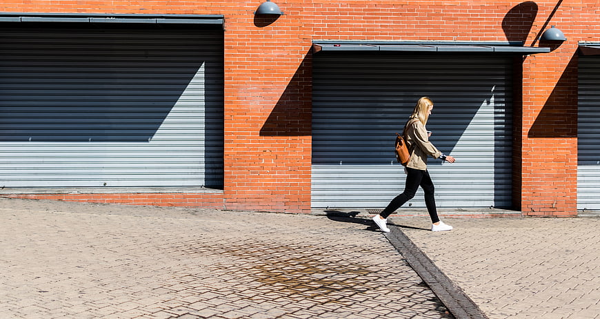 Woman walking past brick wall with garage doors