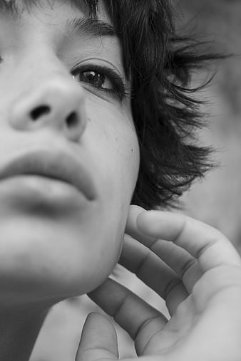 Black and white close-up portrait of a young woman with hand on chin