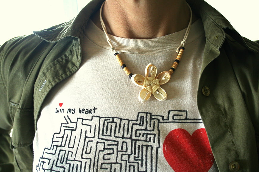 Close-up of handmade cowrie shell flower necklace on graphic tee