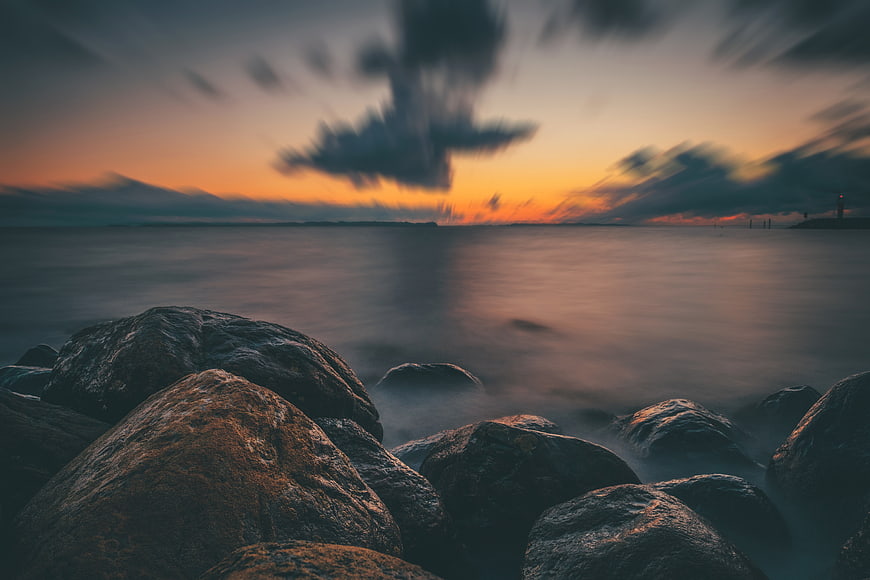 Dramatic Long Exposure Coastal Sunset With Smooth Water And Rocks