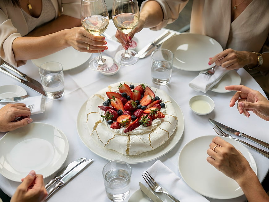 Group of Friends Toasting with Wine Over Pavlova Dessert