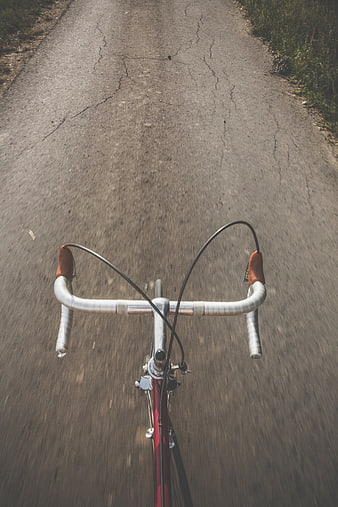 POV shot of bicycle handlebars on cracked asphalt road