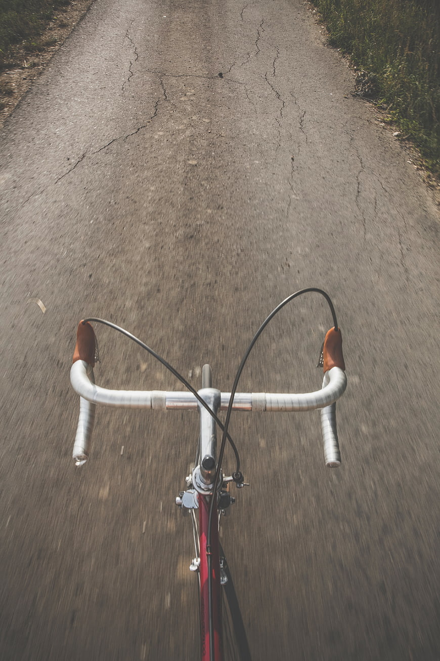 POV shot of bicycle handlebars on cracked asphalt road