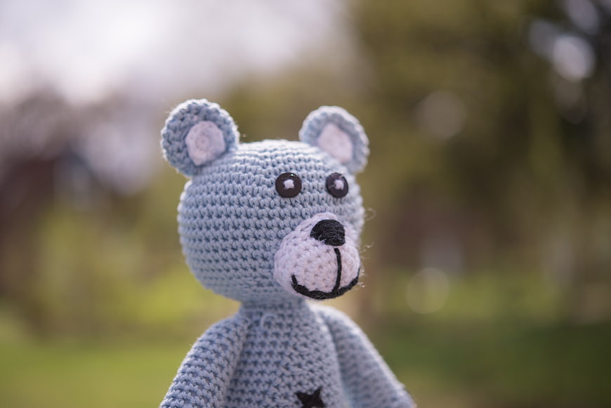 Close-up of a handmade blue crochet teddy bear outdoors