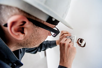 Electrician installing wall socket in white room