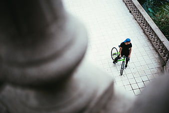 High angle view of cyclist walking with green bike on tiled path