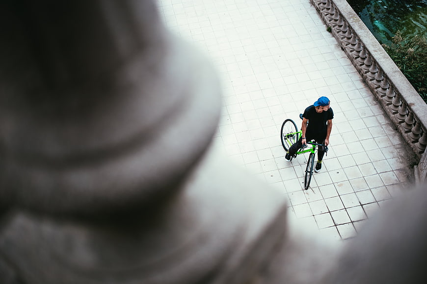 High angle view of cyclist walking with green bike on tiled path