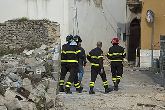 Firefighters walking through rubble in earthquake-damaged Italian street