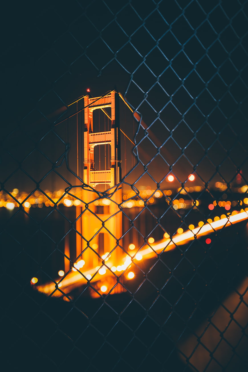 Golden Gate Bridge at Night Through Chain Link Fence