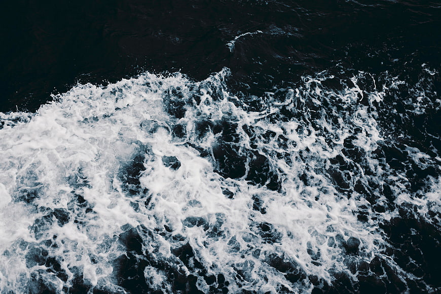 Aerial view of turbulent ocean waves crashing with white foam