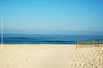 Serene Beach Landscape With Wooden Fence And Calm Ocean