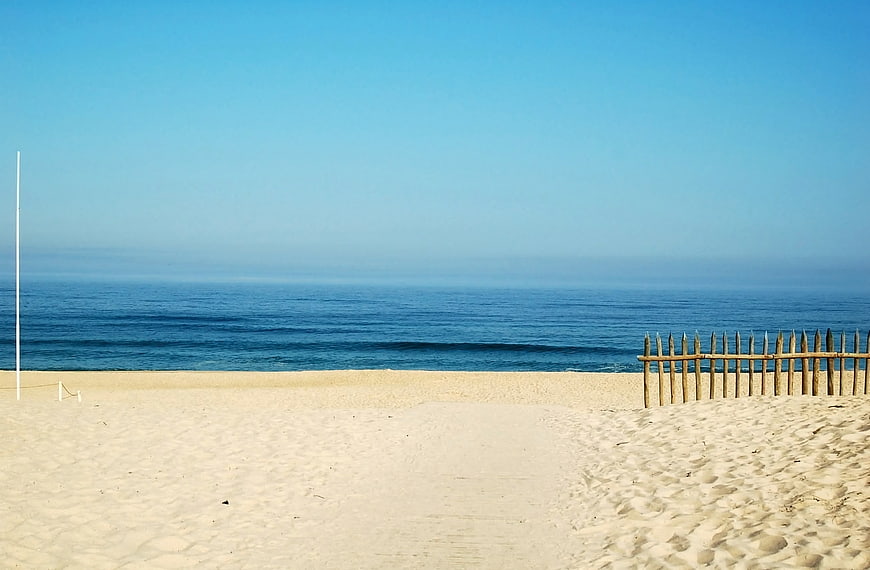 Serene Beach Landscape With Wooden Fence And Calm Ocean