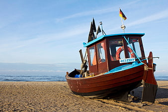 Traditional wooden boat on sandy beach with German flag