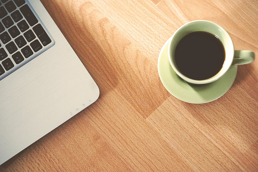 Top View of Coffee Cup and Laptop on Wooden Desk