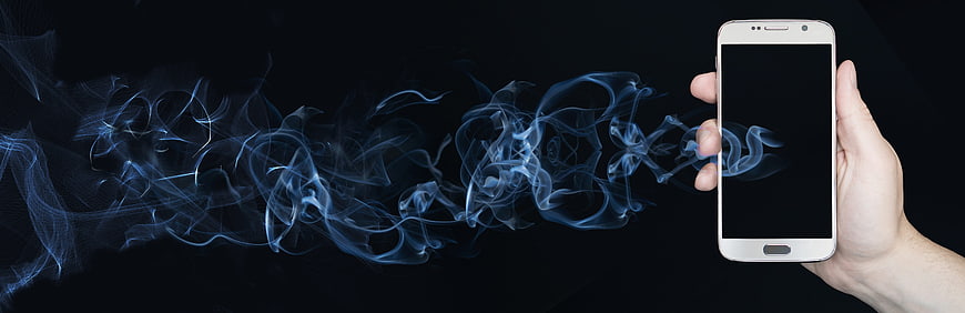 Hand holding smartphone with blue smoke on black background