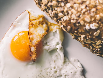 Close-up of fried egg and seeded toast on white plate