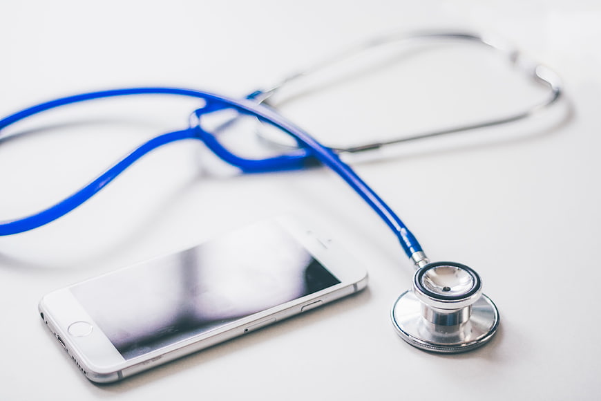 Blue stethoscope and smartphone on white background