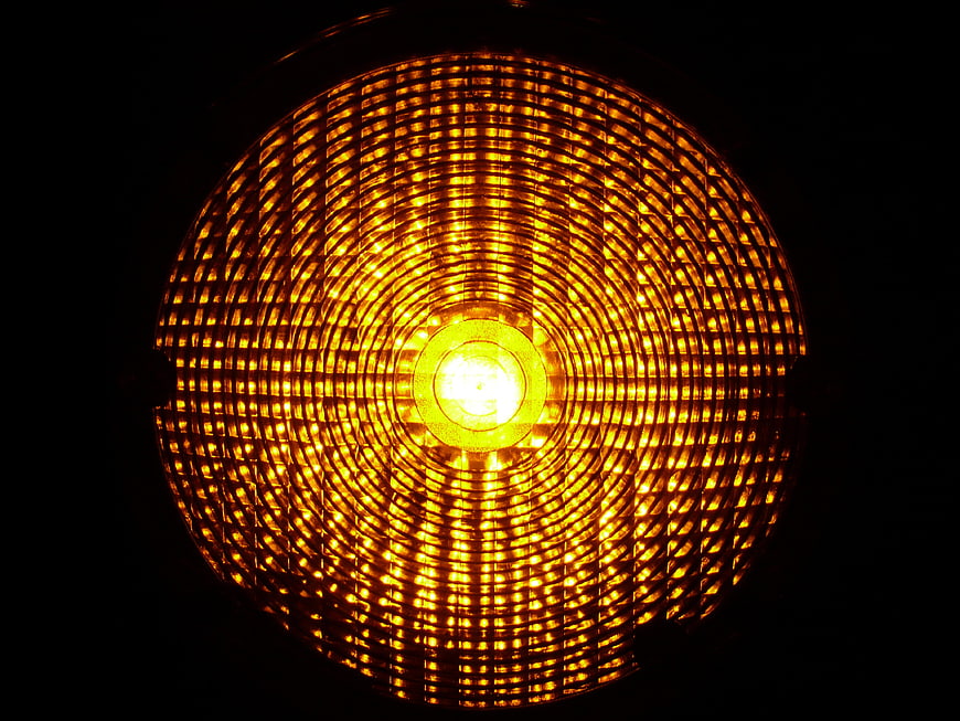 Close-up of glowing amber warning light with grid pattern