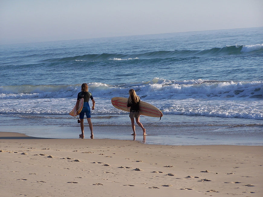 Two surfers walking into ocean waves with boards