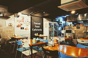 Interior of a casual food cafeteria with wooden tables and blue chairs