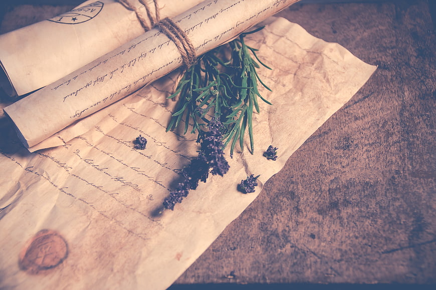 Vintage rolled letters with lavender sprig on rustic wooden table
