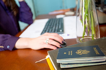 Woman working at desk with passport and computer mouse