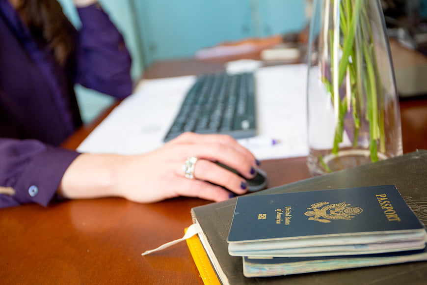Woman working at desk with passport and computer mouse