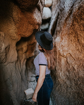 Woman in black hat standing in narrow rock canyon
