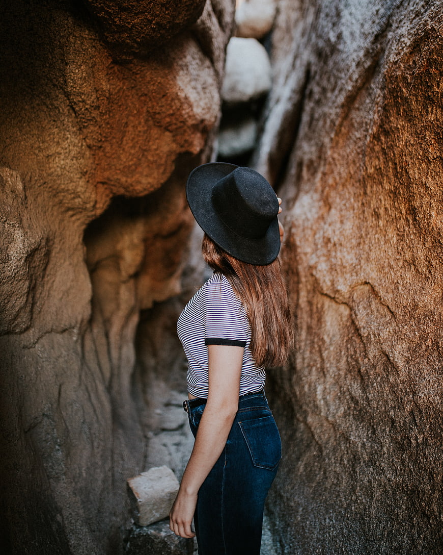 Woman in black hat standing in narrow rock canyon