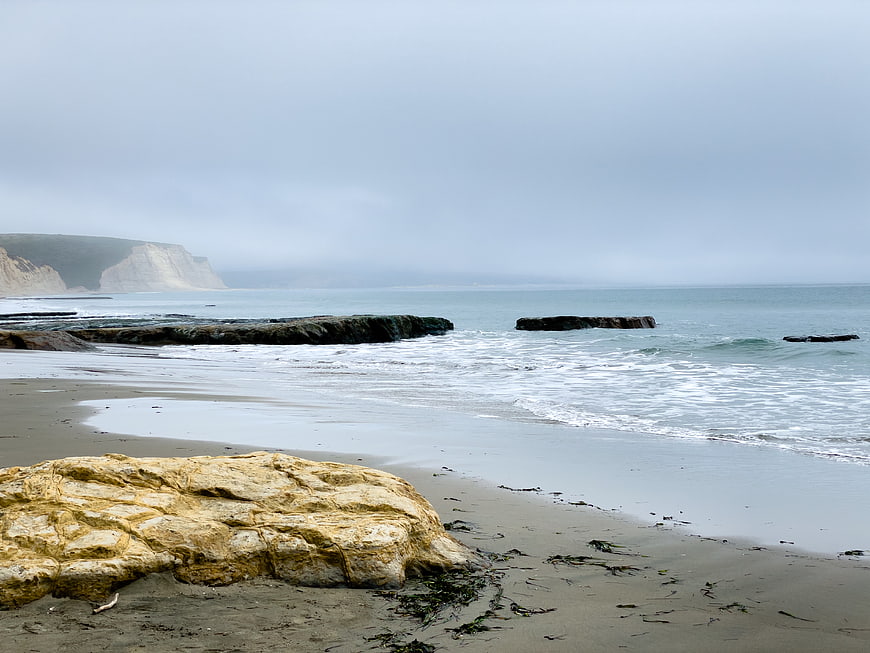 Misty coastal landscape with rocky beach and ocean waves