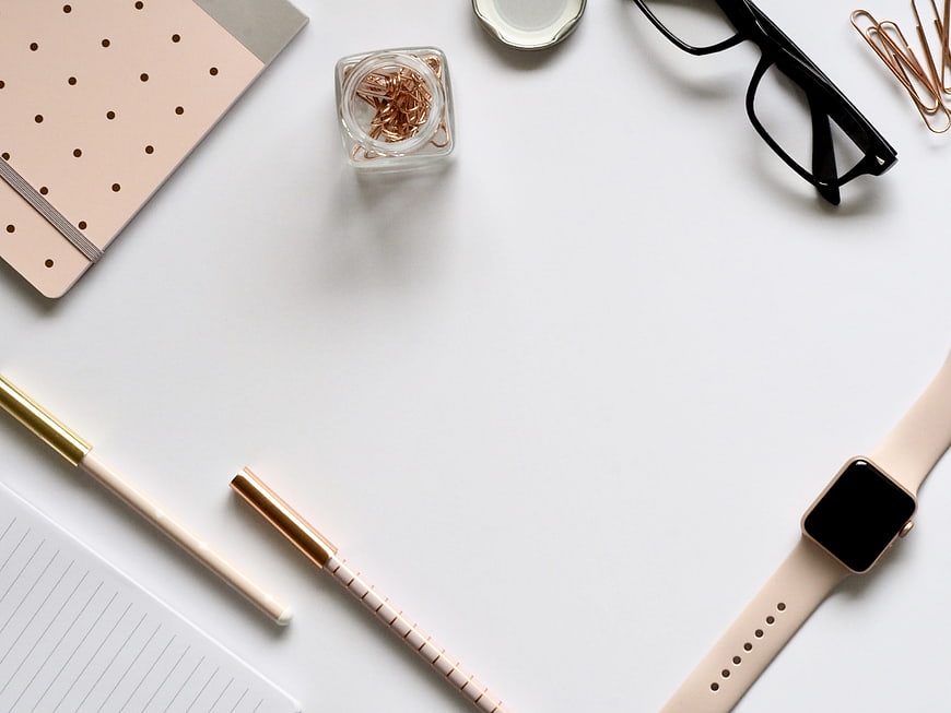 Minimalist workspace flat lay with rose gold accessories and white desk