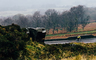 Cyclist riding on rural road through misty highland landscape