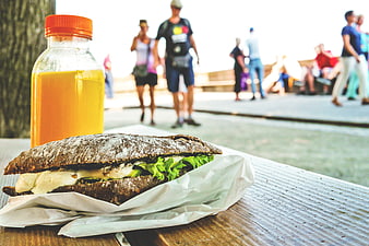 Healthy Sandwich and Juice on Outdoor Table with Blurred People