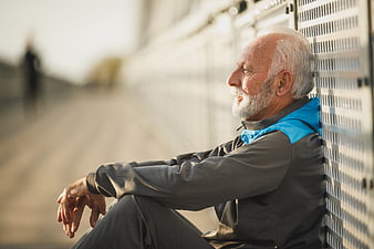 Senior man resting against wall after outdoor workout