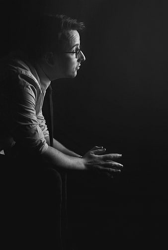 Pensive man in profile with hands clasped in dramatic black and white light