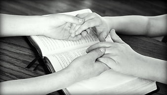 Hands Holding Over Open Bible in Prayer