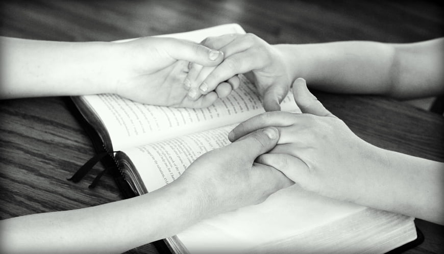 Hands Holding Over Open Bible in Prayer