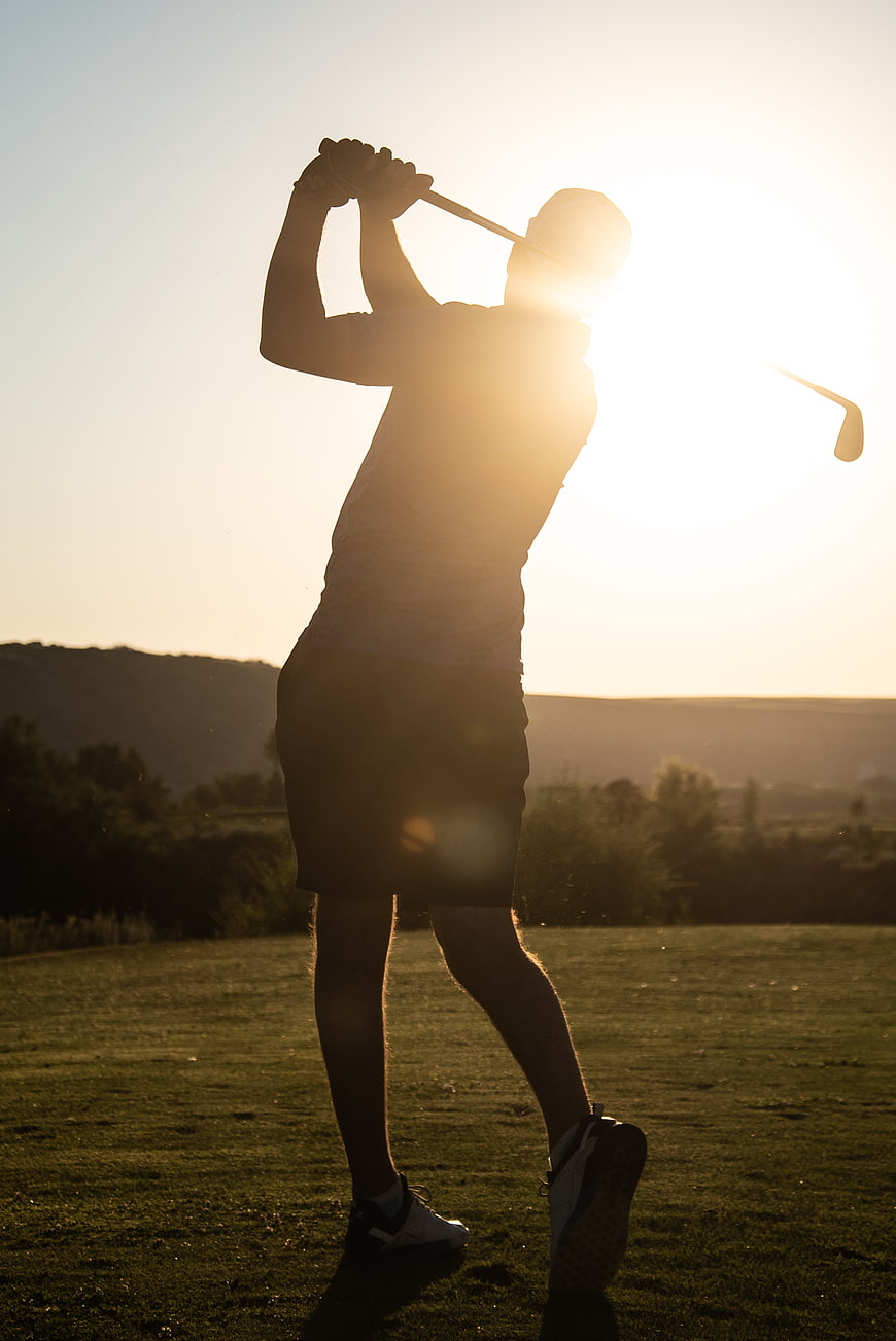 Silhouette of Golfer Swinging Club at Sunset