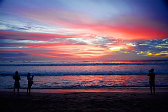 Silhouettes of People Watching Vibrant Sunset at Beach