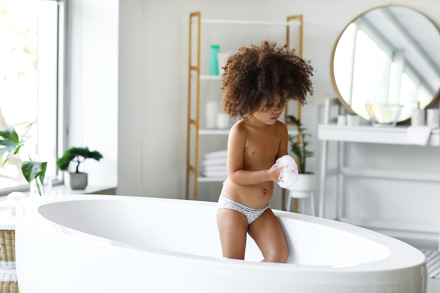 Young Girl Playing with Soap in White Bathtub