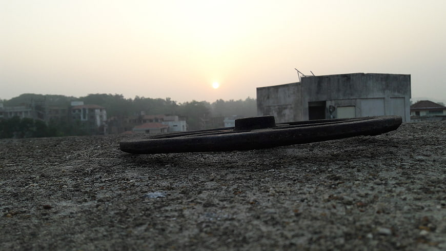 Low angle view of rooftop vent with sunrise and city skyline