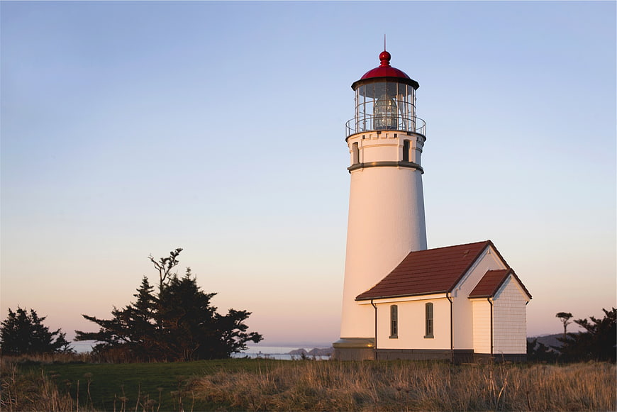 White Lighthouse with Red Roof on Coastal Cliff at Sunset