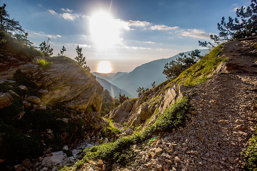 Sunlit Mountain Trail with Rocky Terrain and Distant Peaks
